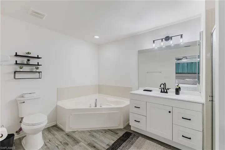 Bathroom featuring a garden tub, vanity, light wood finished floors, a stall shower, and recessed lighting