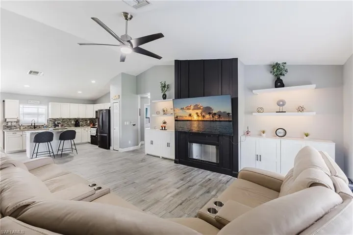 Living area featuring lofted ceiling, ceiling fan, light wood-style flooring, and recessed lighting