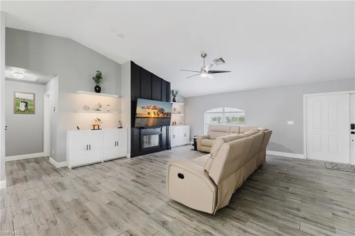 Living area featuring lofted ceiling, wood finish floors, and a ceiling fan
