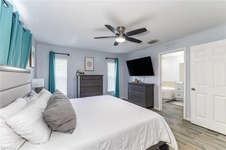 Bedroom with wood finished floors, a ceiling fan, and ensuite bath