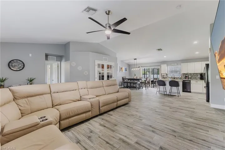 Living room with lofted ceiling, light wood finished floors, and a ceiling fan