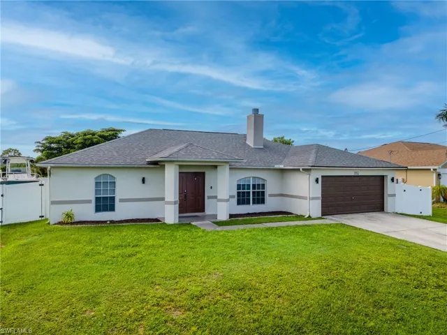 Ranch-style home with a gate, stucco siding, a chimney, and driveway