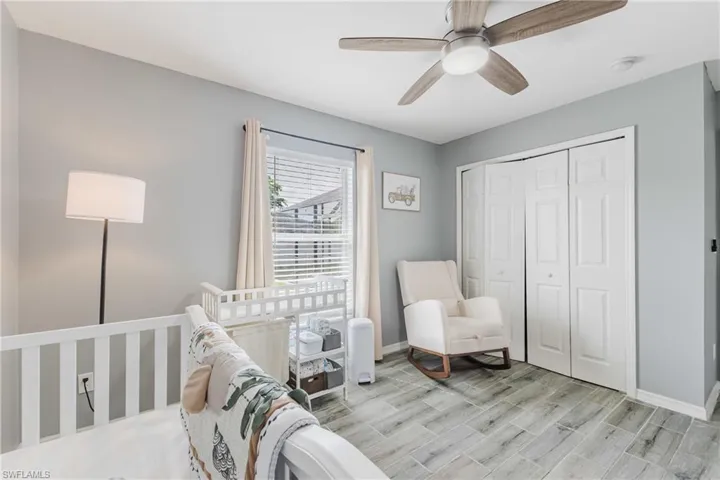 Bedroom with a crib, ceiling fan, a closet, and wood tiled floors