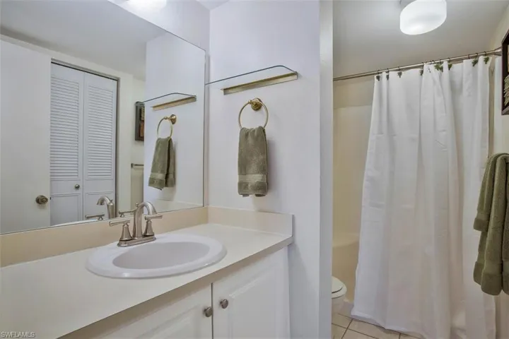 Full bathroom featuring step in shower with seat, tile flooring, large vanity