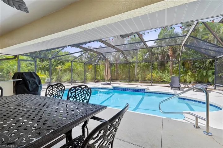 View of pool with a patio area, a grill, and a lanai