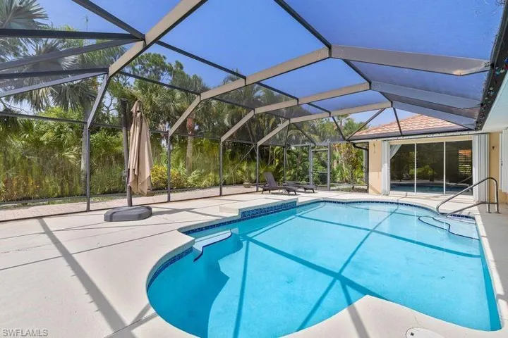 View of pool featuring a patio area and glass enclosure