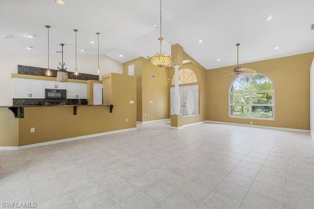 Unfurnished living room with light tile patterned flooring, ceiling fan, and high vaulted ceiling