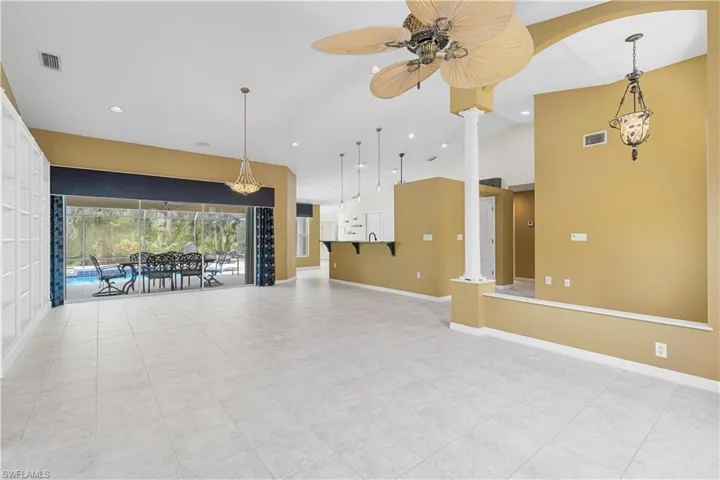 Unfurnished living room with light tile patterned flooring, decorative columns, and ceiling fan