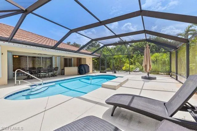View of pool with glass enclosure and a patio area