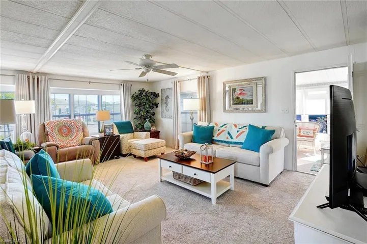 Living room with light carpet, a wealth of natural light, a textured ceiling, and a ceiling fan