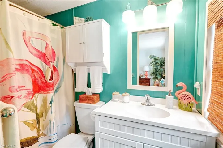 Bathroom featuring curtained shower, toilet, and vanity