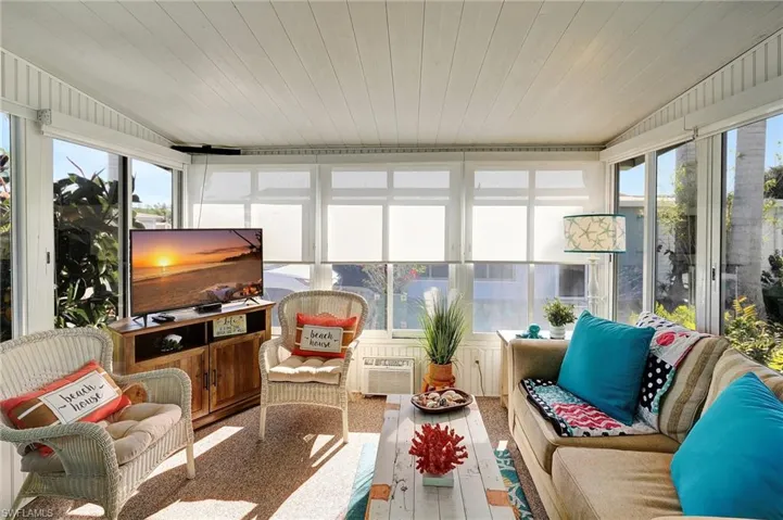 Sunroom with wood ceiling, a wall mounted AC, and lofted ceiling