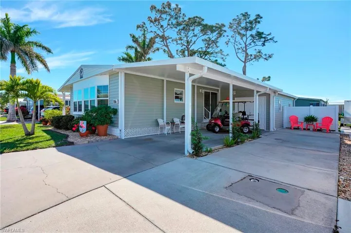 View of front facade with an attached carport, driveway, and fence