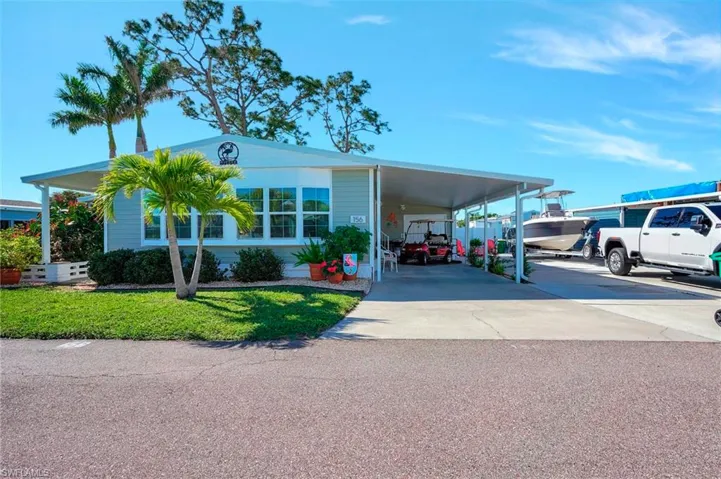 View of front of property featuring an attached carport, driveway, and a front lawn