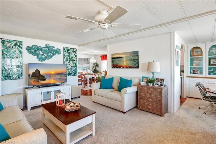 Living room featuring light carpet and a ceiling fan