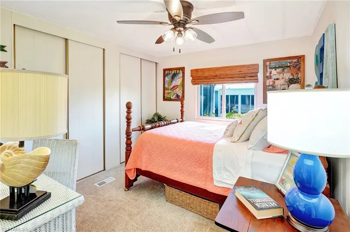 Carpeted bedroom featuring ceiling fan, visible vents, and two closets