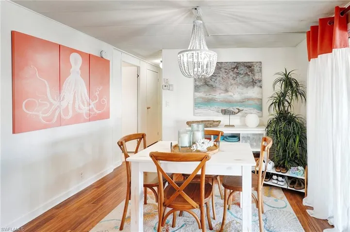 Dining space featuring baseboards, a chandelier, and wood finished floors