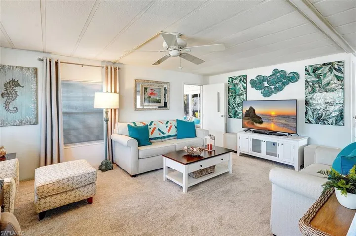Carpeted living room with a ceiling fan and a textured ceiling