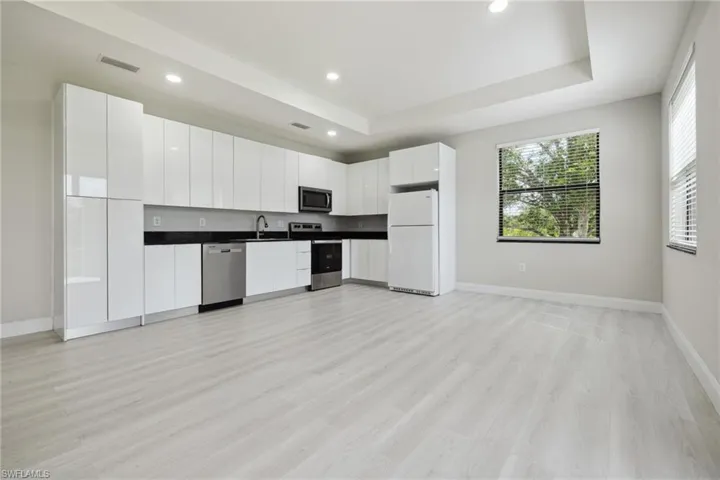 Kitchen with appliances with stainless steel finishes, dark countertops, light wood-style floors, recessed lighting, and white cabinetry