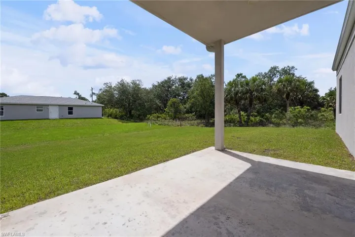 View of green lawn with a patio area