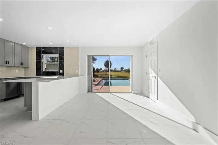 Kitchen featuring gray cabinetry, light marble finish flooring, a breakfast bar area, dishwasher, and recessed lighting