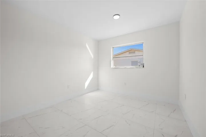 Empty room featuring light marble finish flooring and baseboards
