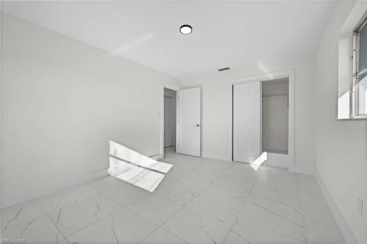 Unfurnished bedroom with light marble finish flooring and a closet
