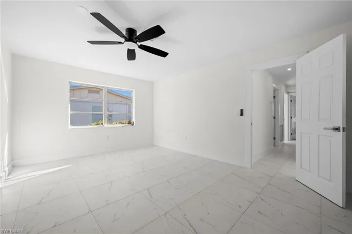 Empty room with light marble finish flooring and a ceiling fan