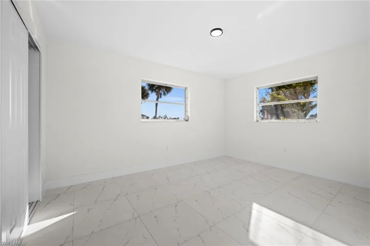 Unfurnished bedroom featuring light marble finish floors and a closet