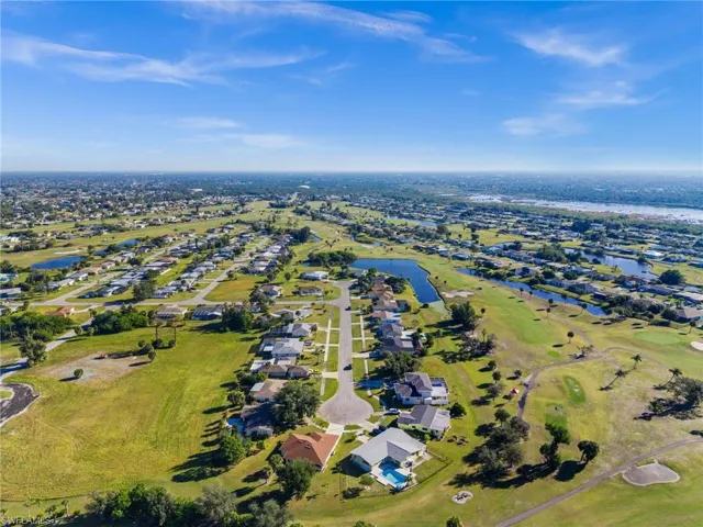 Aerial overview of property's location featuring a nearby body of water, nearby suburban area, and a golf course