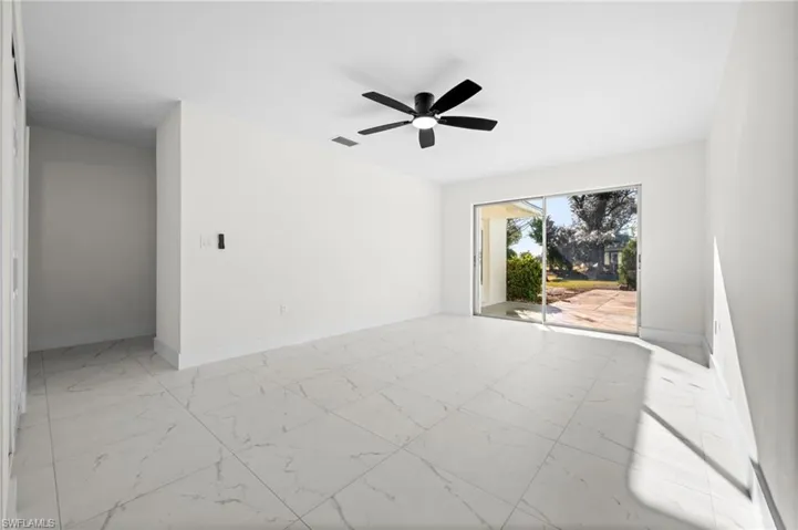 Empty room featuring light marble finish floors and ceiling fan
