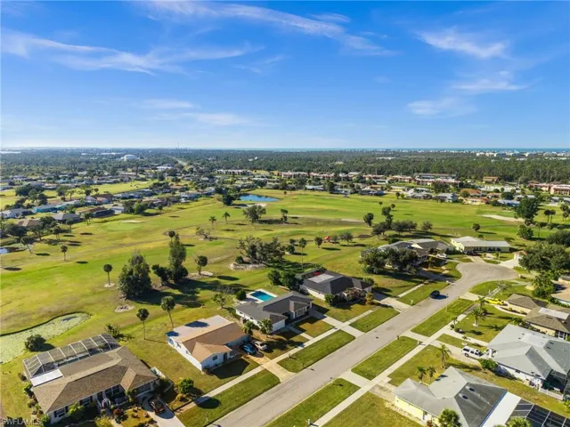 Aerial view of property and surrounding area with nearby suburban area, a nearby body of water, and a golf club