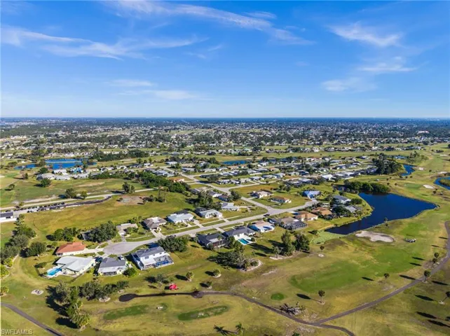 Aerial view of property and surrounding area featuring a nearby body of water, nearby suburban area, and a golf club