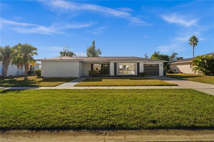 Ranch-style home with concrete driveway, a front yard, and a garage