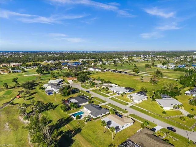 Aerial view of property and surrounding area featuring a local golf course and nearby suburban area