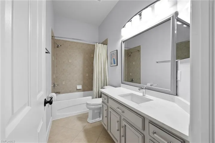 Full bathroom featuring tile patterned floors, vanity, toilet, and shower / bath combination with curtain