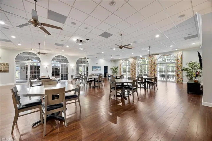 Dining area with ceiling fan, a drop ceiling, and hardwood / wood-style flooring