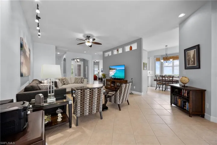Living room featuring ceiling fan, light tile patterned flooring, and track lighting