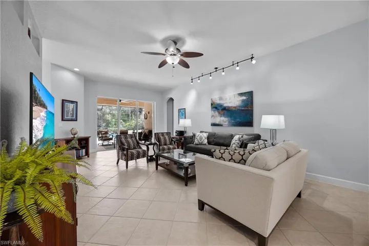 Tiled living room featuring rail lighting and ceiling fan