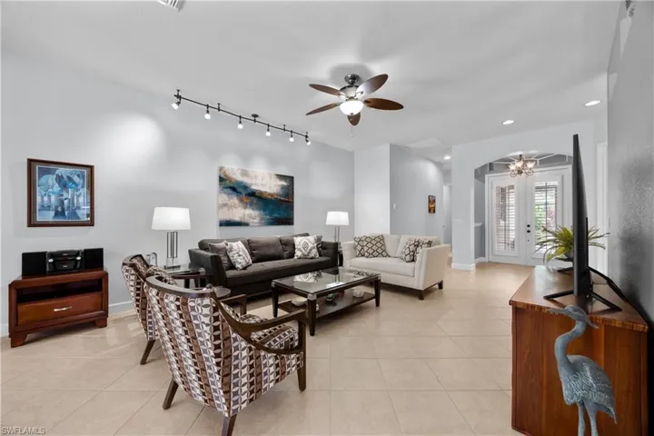 Living room featuring french doors, light tile patterned floors, track lighting, and ceiling fan
