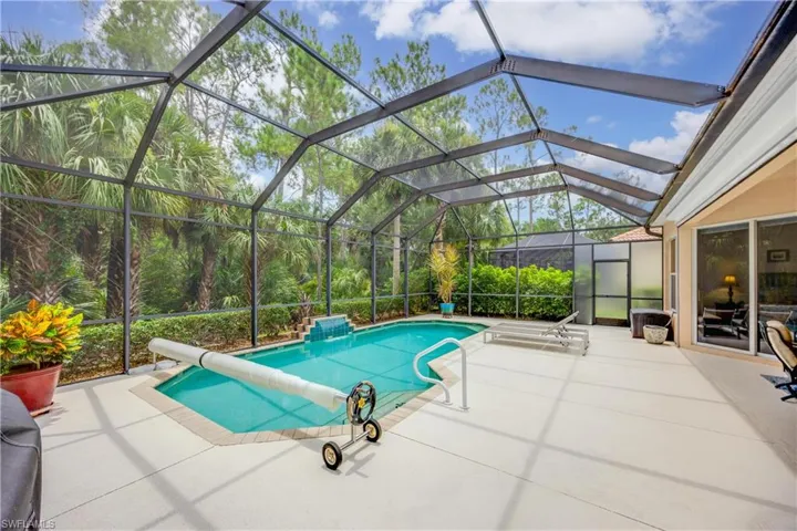 View of swimming pool featuring glass enclosure and a patio area