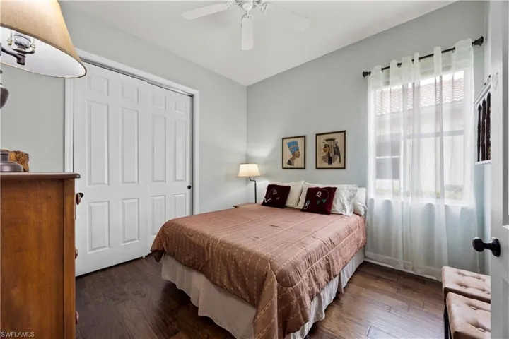 Bedroom featuring ceiling fan, dark hardwood / wood-style flooring, a closet, and multiple windows