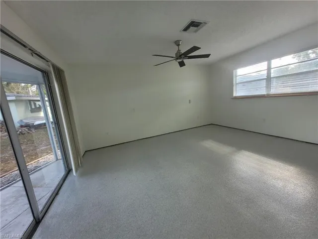 Unfurnished room with plenty of natural light, speckle patterned floor, a textured ceiling, and a ceiling fan