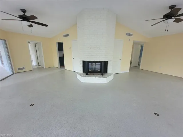 Unfurnished living room featuring ceiling fan, a fireplace, and high vaulted ceiling