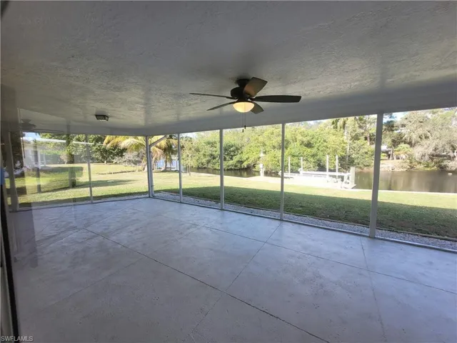 Unfurnished sunroom with a ceiling fan and a water view