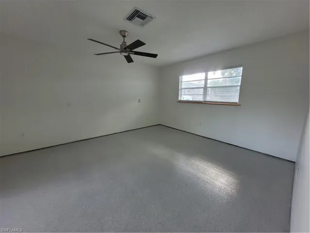 Empty room with a textured ceiling, ceiling fan, and speckle patterned floor