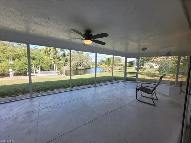 Unfurnished sunroom featuring a ceiling fan and a water view
