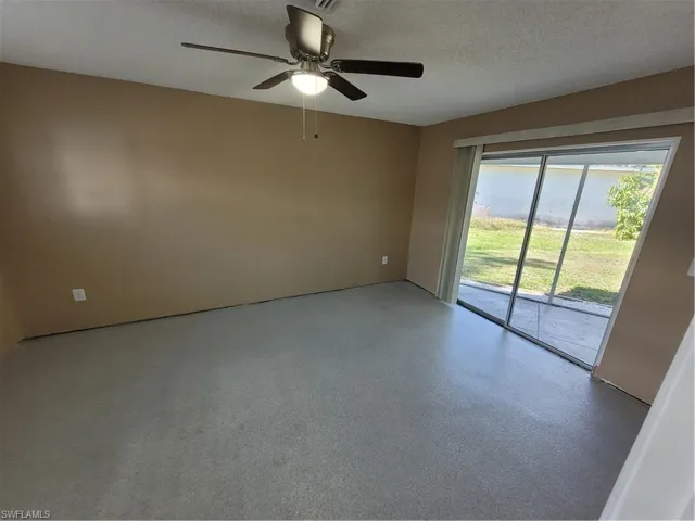 Spare room featuring a textured ceiling, ceiling fan, and speckle patterned floor