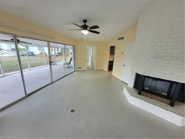 Unfurnished living room featuring a fireplace, ceiling fan, and lofted ceiling