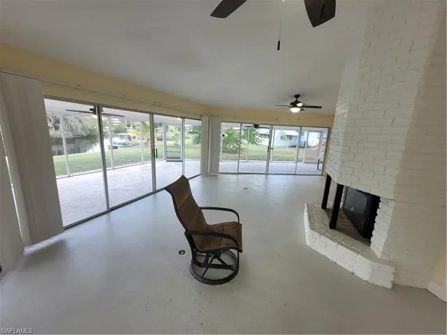 Living area with a water view, a fireplace, finished concrete flooring, and a ceiling fan